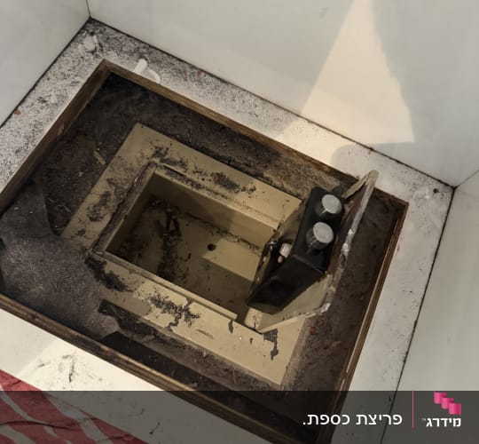 כספת פתוחה בתוך רצפה עם לכלוך מסביב